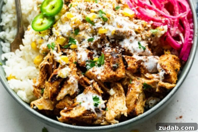 Creamy Esquites Chicken Rice Bowls 5 A street corn chicken rice bowl featuring seasoned chicken breast pieces, creamy elote, rice, sliced jalapeños, and pickled red onions, ready to be enjoyed.