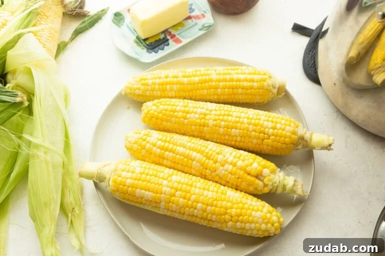 How to Cook Corn on the Cob Perfectly Every Time 2 four ears of bright yellow corn sitting on a large dinner plate