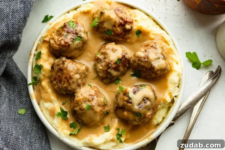 Classic Swedish Meatballs with Creamy Gravy 2 a bowl of creamy Swedish meatballs on a bed of mashed potatoes and sprinkled with fresh parsley