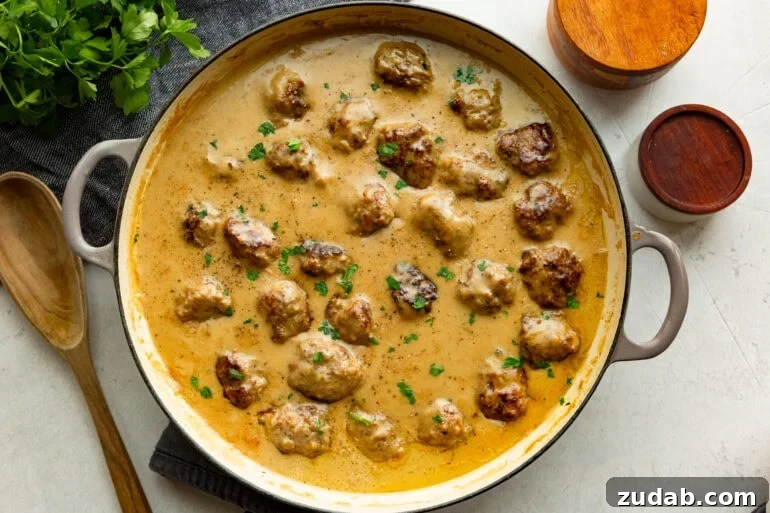 Classic Swedish Meatballs with Creamy Gravy 8 a large dutch oven full of golden brown Swedish meatballs sitting in a thick gravy sauce