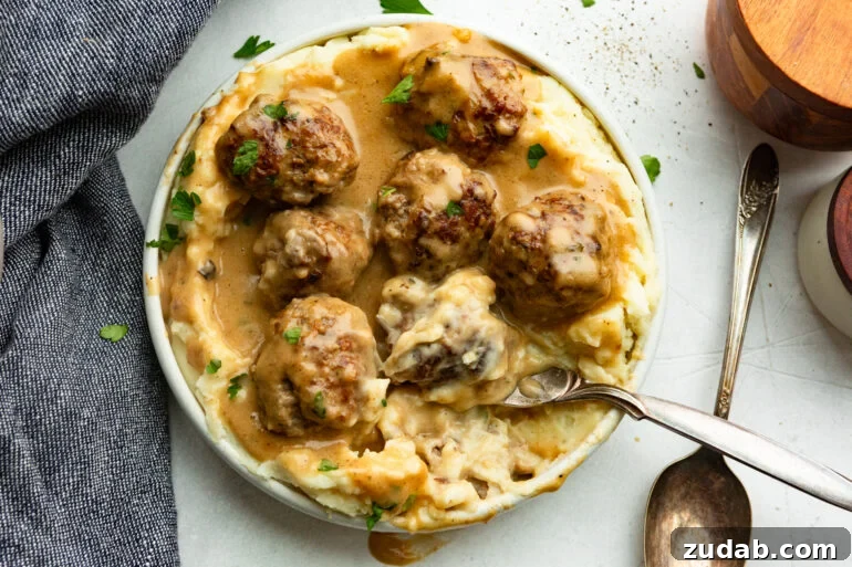 Classic Swedish Meatballs with Creamy Gravy 9 a spoon scooping up a Swedish meatball on top of mashed potatoes