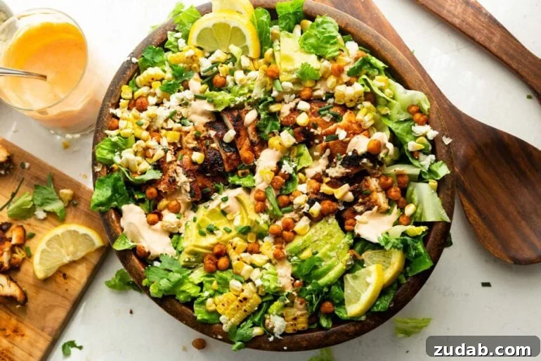 Southwest Ranch Grilled Chicken Salad Recipe 5 a large wooden bowl full of grilled chicken breast, sliced avocado, corn, crispy chicken peas and drizzled with southwest ranch