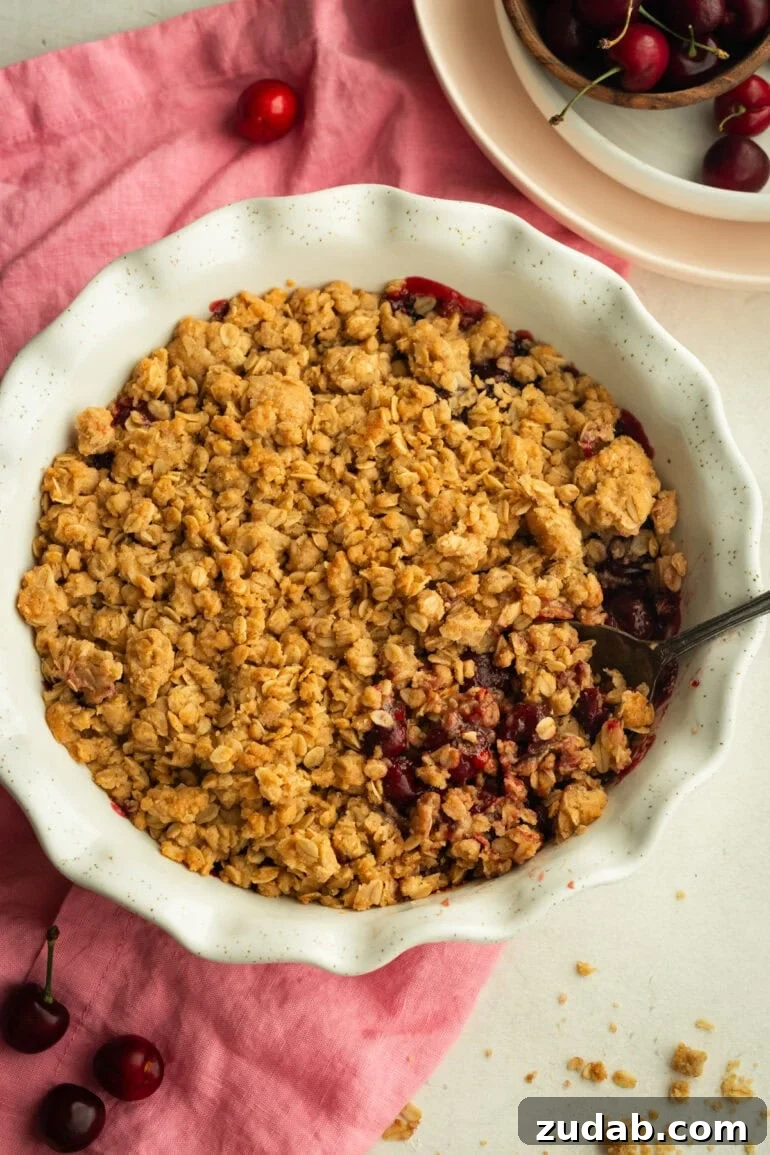 Classic Old-Fashioned Cherry Crisp with Oat Topping 5 a circular white baking dish full of baked cherry crisp topped with golden oat topping
